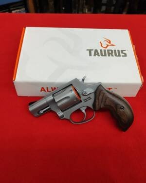 Taurus 856 Executive Stainless 38 Special revolver with walnut grips in front of factory box