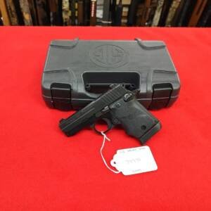 Sig Sauer P938 Rubber Grip 9mm handgun resting in front of factory case